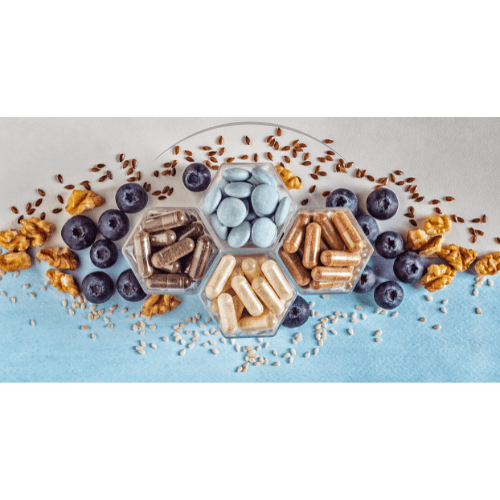 Hexagonal containers with various dietary supplements surrounded by blueberries, flax seeds, and walnuts on blue and white background
